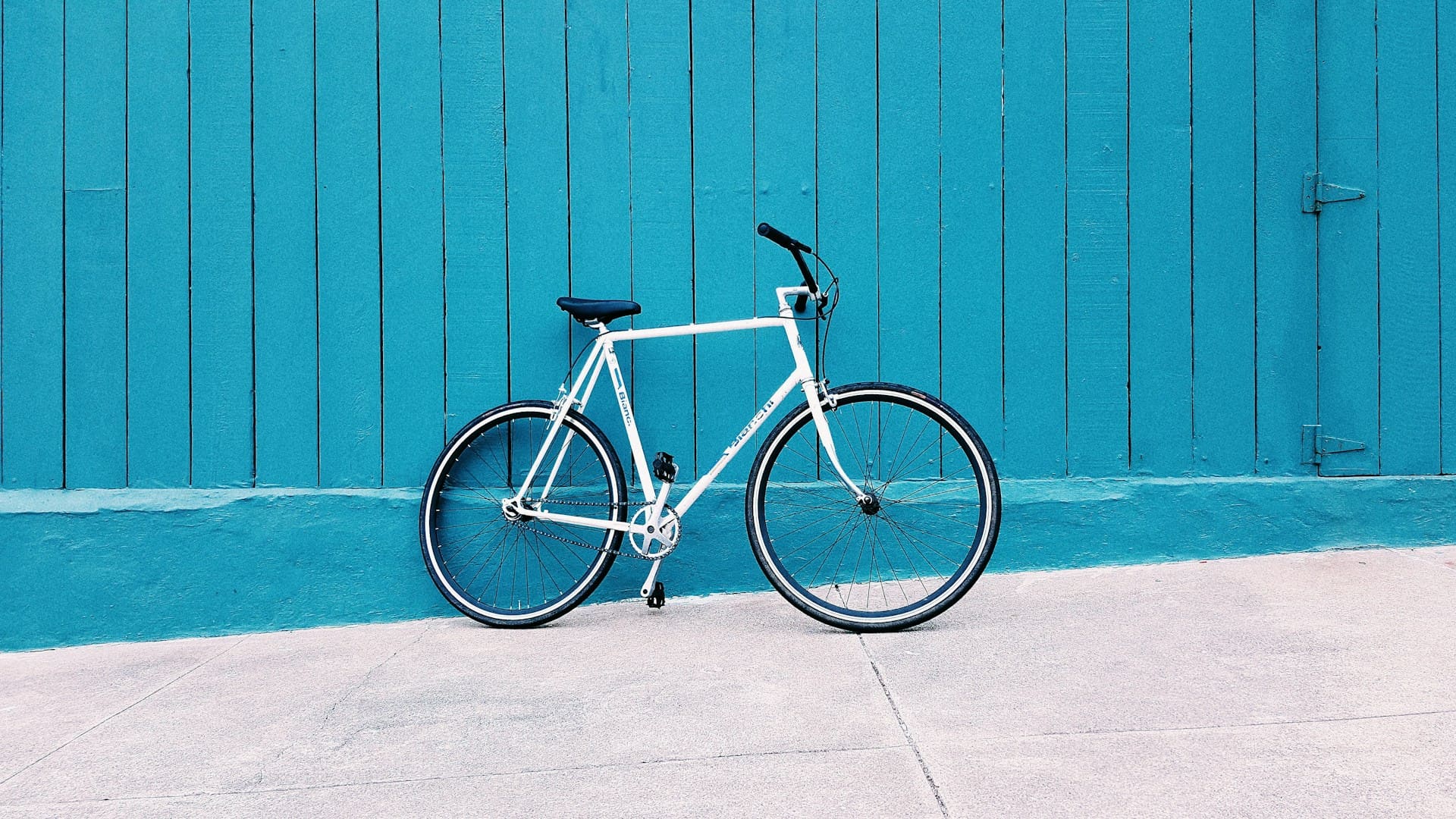 Fiets leasen voor in de stad: witte stadsfiets tegen een blauwe houten wand.