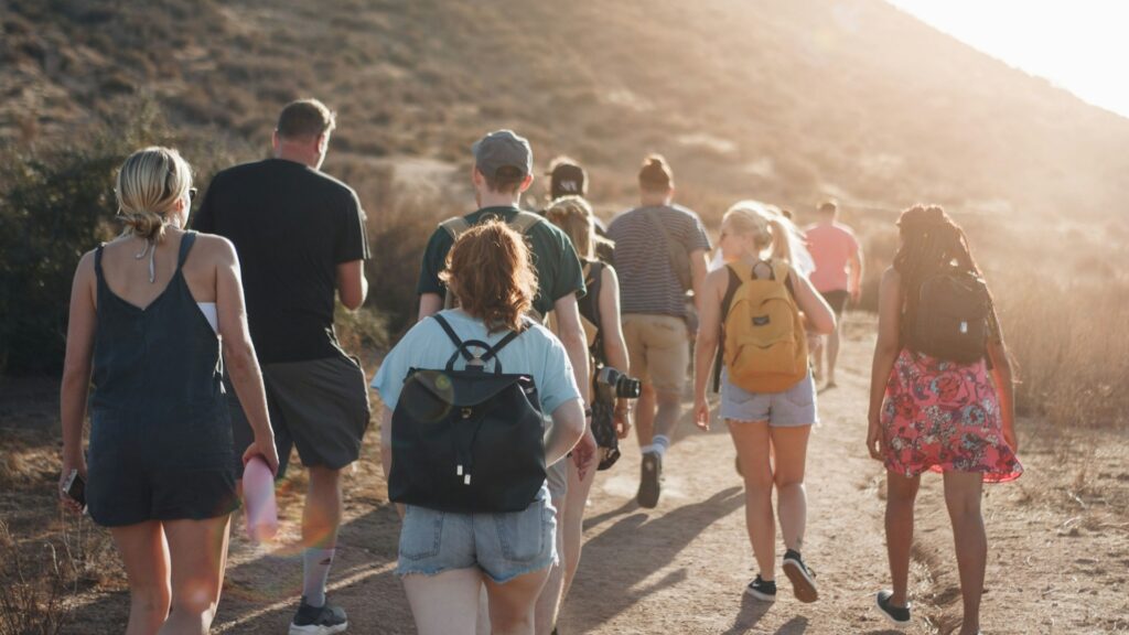 Jongeren wandelen samen tijdens reizen na je studie over een zonnig pad met rugzakken in de natuur