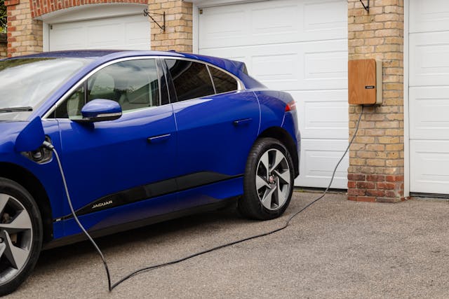 Een elektrische auto die op de oprit van een huis aan de oplaadpaal staat op te laden