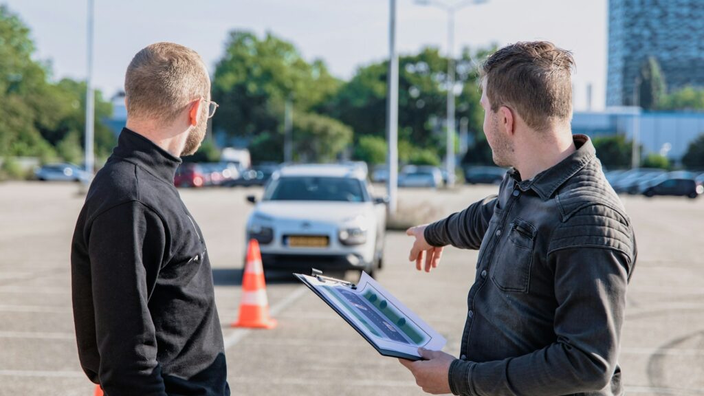 Rijinstructeur geeft uitleg tijdens praktijkles op parkeerterrein, relevant voor prijs rijlessen en lesopbouw